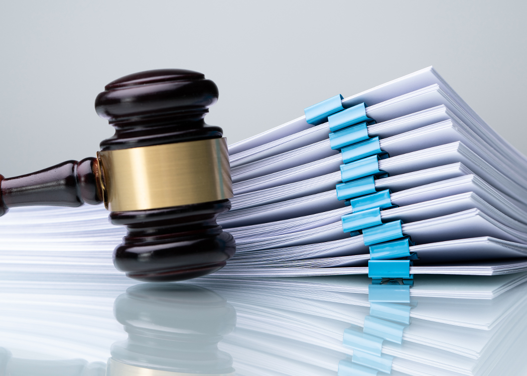 A gavel in front of a a stack of documents.