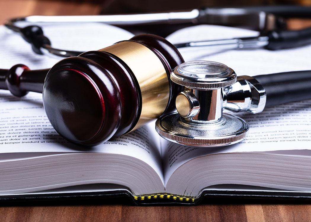 Close up of a gavel and stethoscope on an open book.